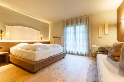 a bedroom with a large bed and a window at Romantik Hotel Post in Nova Levante