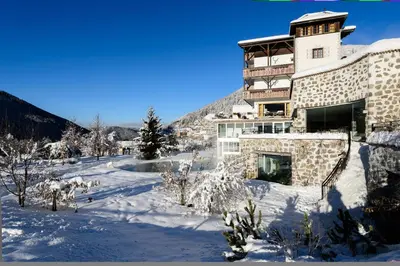 a large building in the snow in front of a mountain at Romantik Hotel Post in Nova Levante