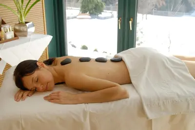 a woman laying on top of a bed at Romantik Hotel Post in Nova Levante