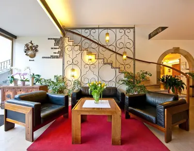 a lobby with black leather couches and a coffee table at Hotel Elefant in Ora/Auer