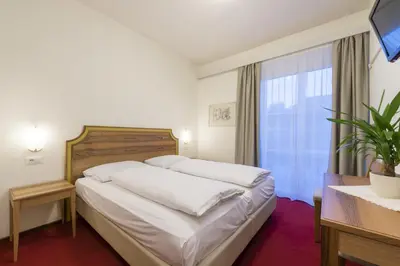 a bedroom with a bed and a large window at Hotel Elefant in Ora/Auer