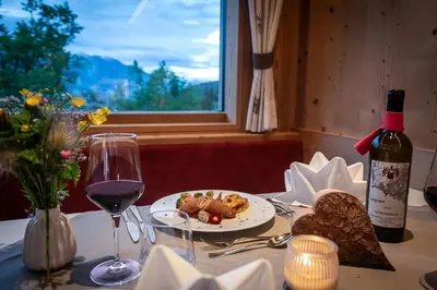 a table with a plate of food and a bottle of wine at Moarlhof - Farm Nature Resort in Castelrotto