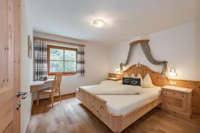 a bedroom with a bed and a desk and a window at Moarlhof - Farm Nature Resort in Castelrotto