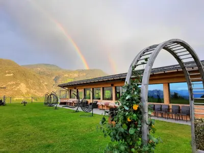 a rainbow in the sky over a pavilion with a playground at Moarlhof - Farm Nature Resort in Castelrotto