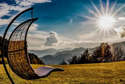 a swing in a field with the sun in the background at Moarlhof - Farm Nature Resort in Castelrotto
