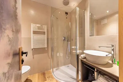 a bathroom with a glass shower and a sink at Hotel Faloria in Moena