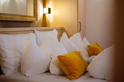 a pile of pillows on a bed with a mirror at Hotel Faloria in Moena