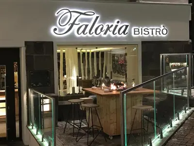 a restaurant with a bar with stools in front of it at Hotel Faloria in Moena