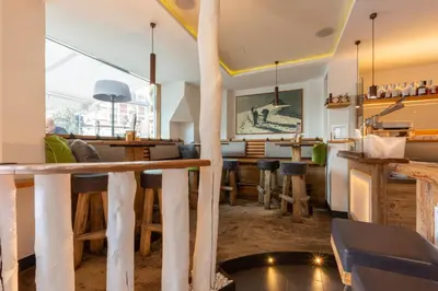 a restaurant with a bar with wooden tables and chairs at Hotel Faloria in Moena