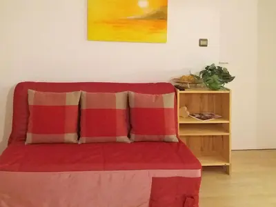 a bed with a red and white blanket and a table at Appartements Erika in Falzes