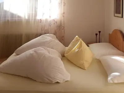 four white pillows sitting on a bed with a window at Appartements Erika in Falzes