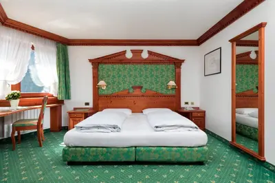 a bedroom with a bed and a table and a mirror at Garni Criss in Colfosco