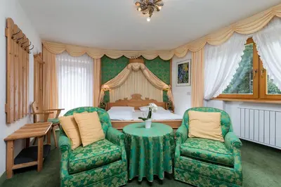a bedroom with a bed and two chairs and a table at Garni Criss in Colfosco