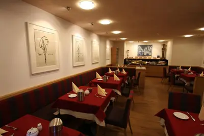 a restaurant with red tables and chairs in a room at Garni Criss in Colfosco