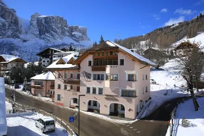 a building in the snow with a car parked in front at Garni Criss in Colfosco