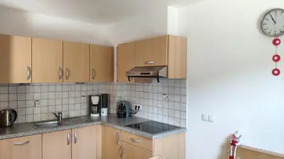 a kitchen with wooden cabinets and a clock on the wall at Thalerhof in Prenn