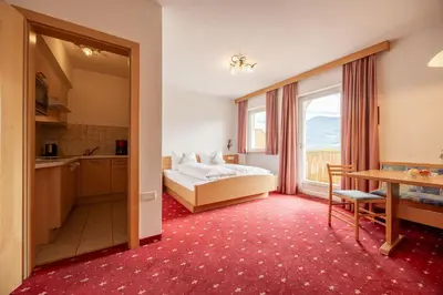 a bedroom with a bed and a kitchen with a window at EGGER Apartments & Suites in Villandro