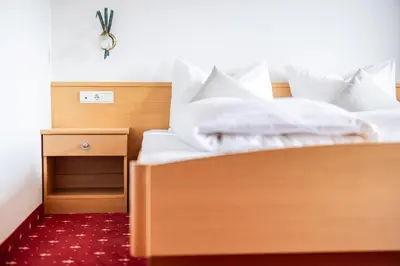 a bed with white sheets and pillows on it at EGGER Apartments & Suites in Villandro