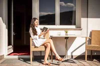 a woman sitting at a table reading a book at EGGER Apartments & Suites in Villandro