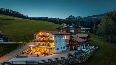 a large building on a hill with cars parked at Hotel Schmiedhof in Maranza
