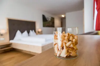 a glass vase filled with pasta on a table with a bed at Hotel Schmiedhof in Maranza