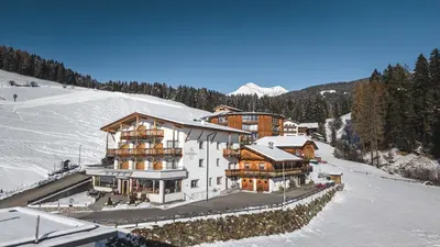 a large building on top of a snow covered mountain at Hotel Schmiedhof in Maranza