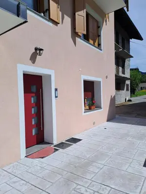 a pink building with a red door and two windows at Casa Vanna in Mezzano