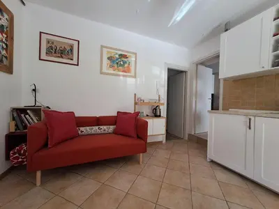 a living room with a red couch and a kitchen at Casa Vanna in Mezzano