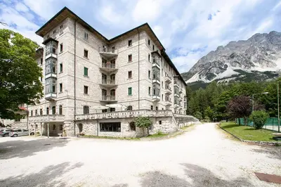 an empty hall with chairs and a piano in the background at TH Borca di Cadore - Park Hotel Des Dolomites in Borca di Cadore