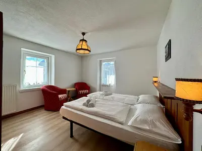 a bedroom with a large white bed and two windows at Central Apartment Canazei in Canazei