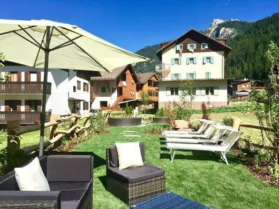 a group of chairs and an umbrella in a yard at Central Apartment Canazei in Canazei