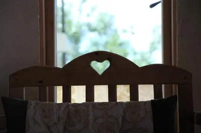 a wooden headboard with a heart in a window at Hotel Alle Ciaspole in Fondo