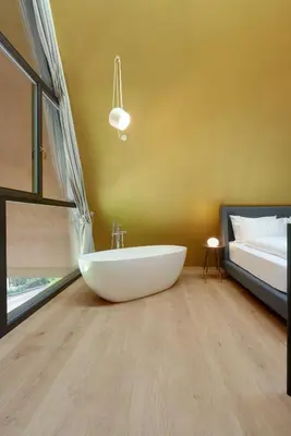 a bathroom with a white tub on the floor next to a bed at Villa Baronessa in Caldaro