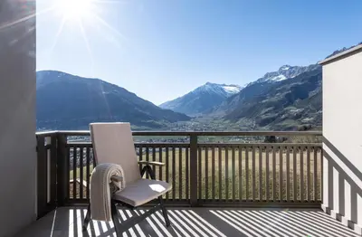 a balcony with a chair and a view of mountains at Hotel Sonnbichl in Tirolo