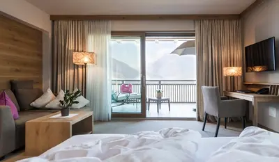 a hotel room with a bed and a balcony at Hotel Sonnbichl in Tirolo