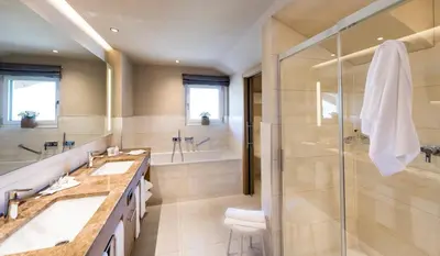 a bathroom with two sinks and a shower at Hotel Sonnbichl in Tirolo