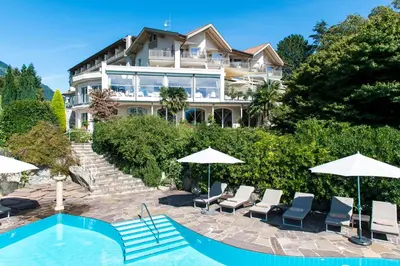 a large house with a pool and chairs and umbrellas at Hotel Sonnbichl in Tirolo