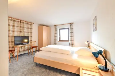 a bedroom with a bed and a desk and a television at Gasthof Ebner Pfiffikus in Aldino