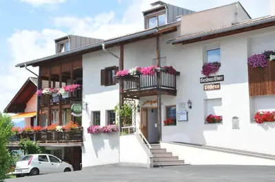 a white building with flowers on the balconies at Gasthof Ebner Pfiffikus in Aldino