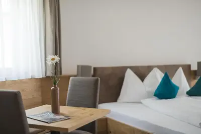 a hotel room with a table and a bed and a vase with a flower at Apparthotel Zunneler in Schenna