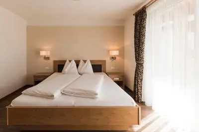 a bedroom with a bed with white sheets and a window at Apparthotel Zunneler in Schenna