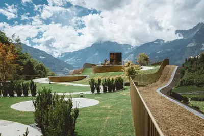 a house on a hill with mountains in the background at Prinz Rudolf Smart Hotel in Merano