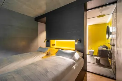 a bedroom with a large bed and a yellow wall at Prinz Rudolf Smart Hotel in Merano