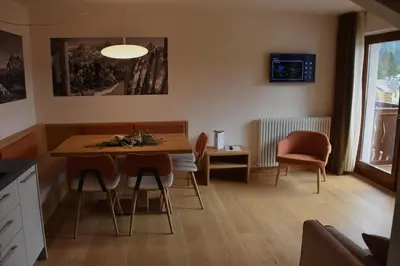 a dining room with a table with chairs and a television at Residence Langes in San Martino di Castrozza
