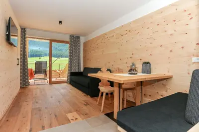 a room with a wooden wall with a table and a couch at Lerchnhof in Valdaora