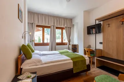 a hotel room with a bed and a window at Hotel Oswald in Canazei