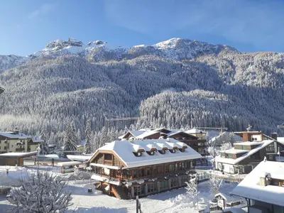 a resort in the snow with mountains in the background at Hotel Oswald in Canazei