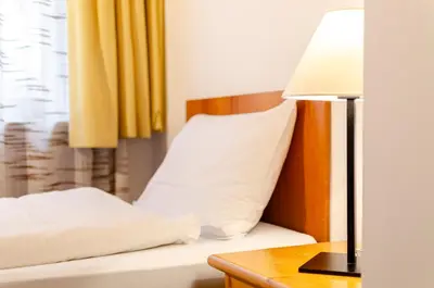 a bed with a pillow and a table with a lamp at Hotel Oswald in Canazei