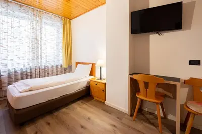a hotel room with a bed and a window at Hotel Oswald in Canazei
