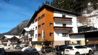 a large building with cars parked in a parking lot at Hotel Oswald in Canazei